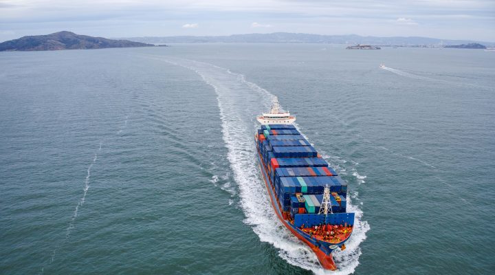 A large container ship navigating in open water, representing industries benefiting from vibration monitoring for machinery health.