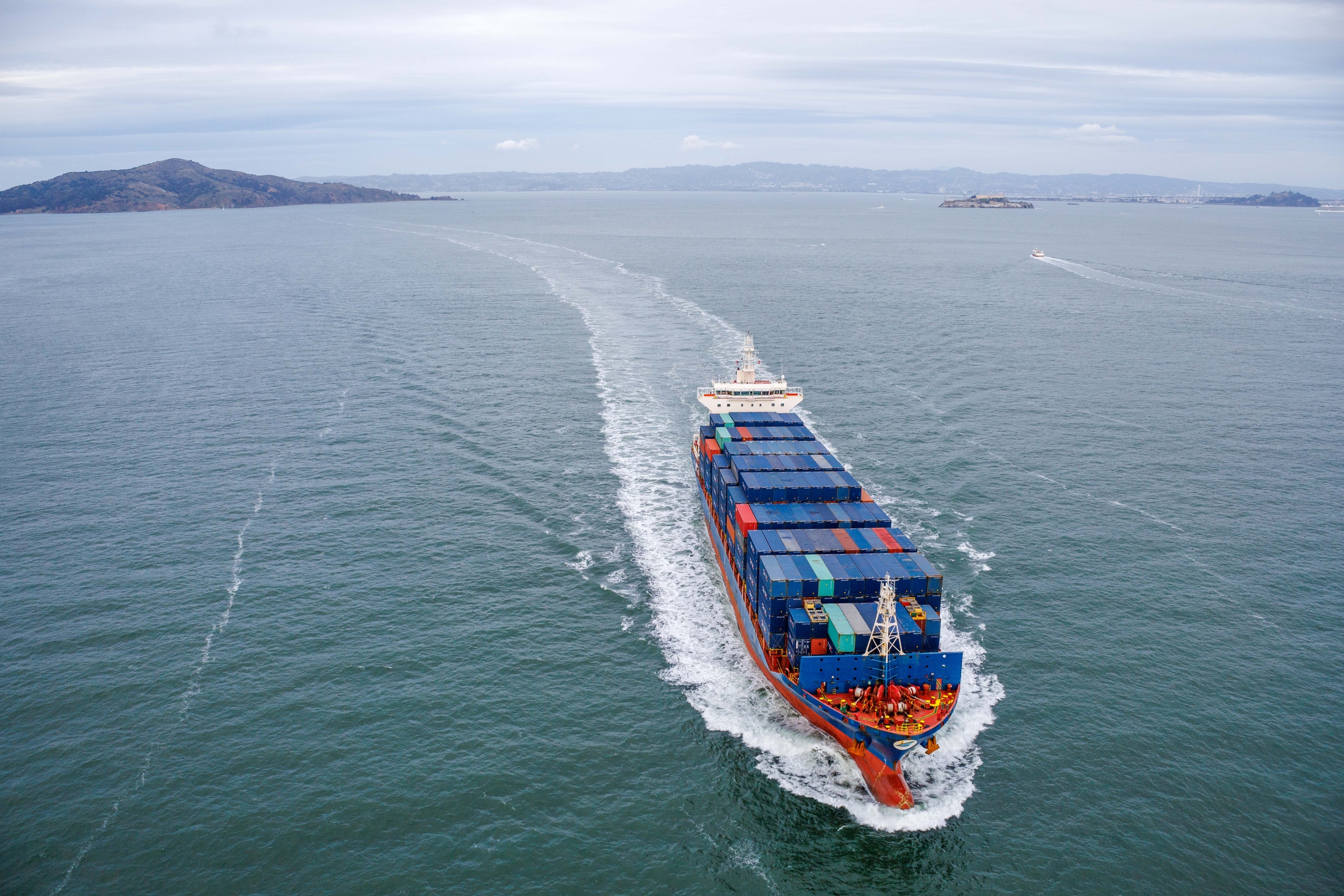 A large container ship navigating in open water, representing industries benefiting from vibration monitoring for machinery health.